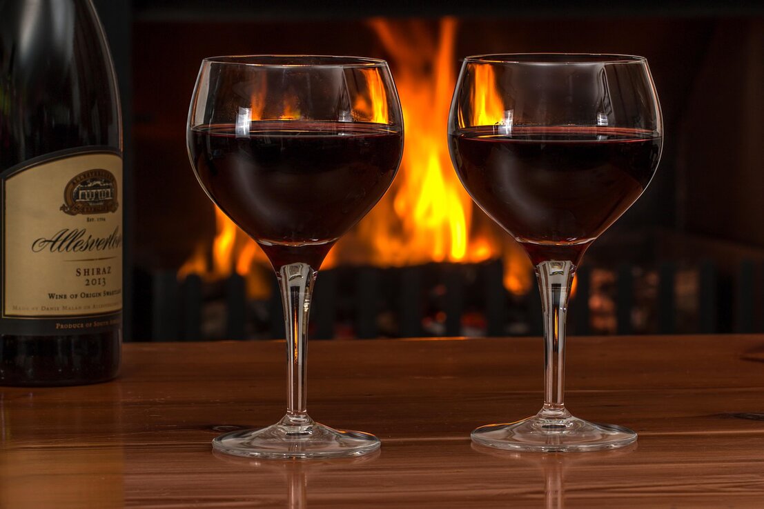 Tavola apparecchiata con calice di vino rosso